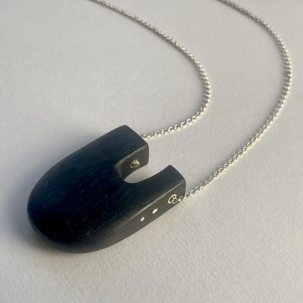 Dark wood u-shaped pendant with silver inlay on a silver chain